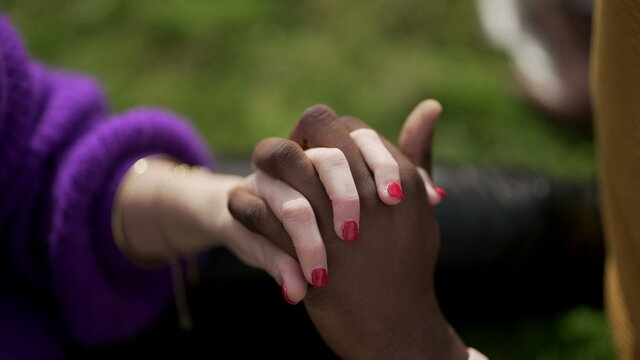 Ethnically diverse couple holding hands close-up. Mixed race woman and black man showing love and affection