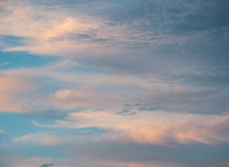 pretty sunrise sky nature photo with clouds with pink and golden tones in blue sky.
