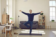 © Studio Romantic - Senior man taking break from work in business office. Happy calm mature businessman doing Vrikshasana or Tree Pose with eyes closed while practising yoga exercise during working day in his workplace