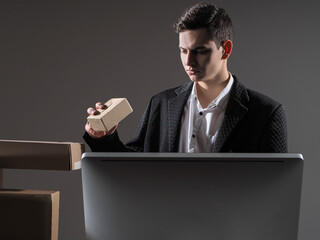 Poster - Logistic, small business. Businessman is engaged in the delivery of parcels. Company that delivers goods. Man with a cardboard box is standing next to PC. Electronic business. E-commerce concept.