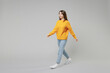 © ViDi Studio - Full length of young smiling positive student caucasian happy cheerful optimistic woman 20s wearing knitted yellow sweater walking going strolling isolated on grey color background studio portrait