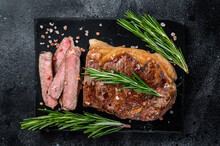Cut Roasted New York Strip Beef Meat Steak Or Striploin On A Marble Board. Black Background. Top View