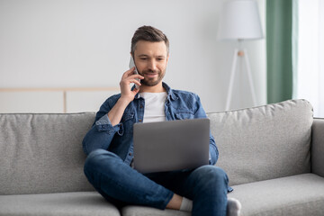 Wall Mural - Positive middle-aged man with laptop talking on smartphone