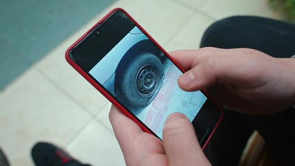 Poster - Phone screen showing car wheel chopped rubber. Damage to vehicles in street fights. Scrolling movement with your fingers.