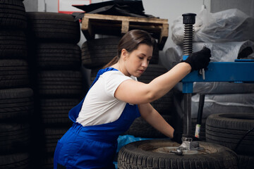 Female mechanic uses a machine tool in a garage