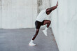© VISTA by Westend61 - Sportsman doing stretching workout while leaning on white wall