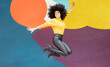 © VISTA by Westend61 - Cheerful woman jumping with arms outstretched against colorful wall