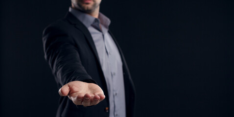 Canvas Print - Businessman with outstretched hand on dark background