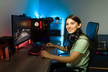 Portrait of a female gamer with headphones in front of her gaming PC