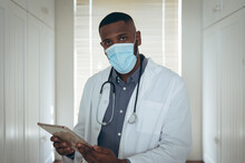Portrait Of African American Male Doctor Wearing Face Mask Using Digital Tablet