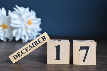 December 17, Date cover design with calendar cube and white Paeonia flower on wooden table and blue background.	
