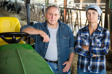 Dairy farm workers standing near tractor, communicating during break in work