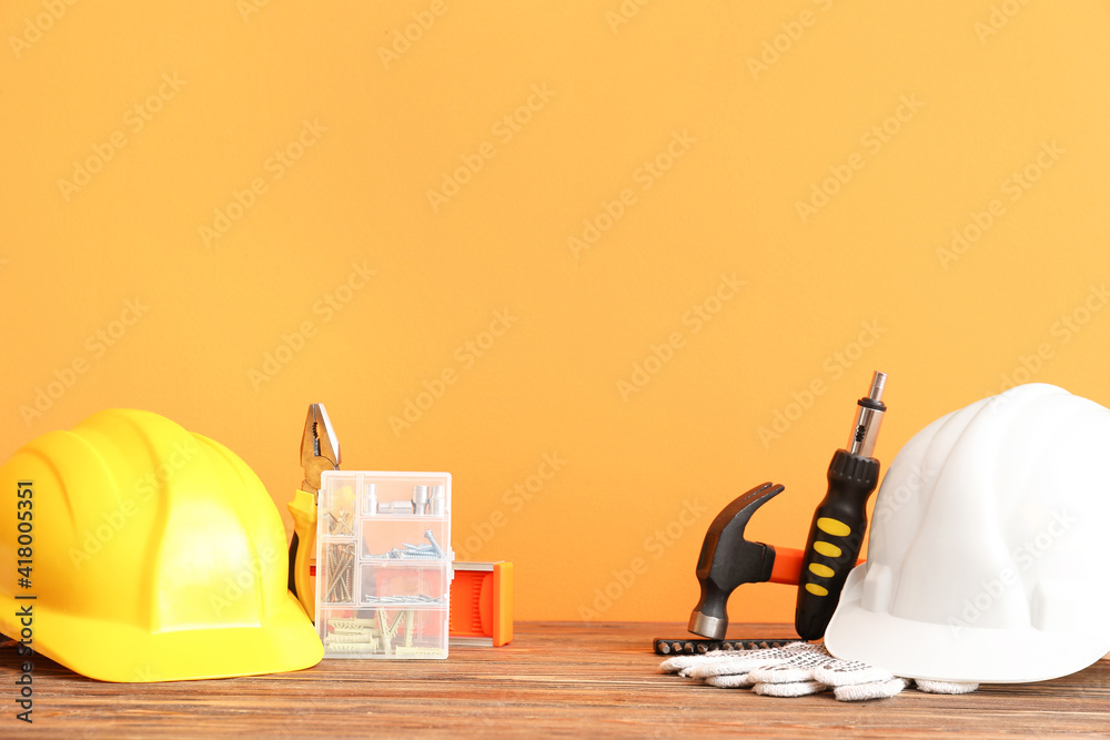 Set of construction tools on wooden table against color background