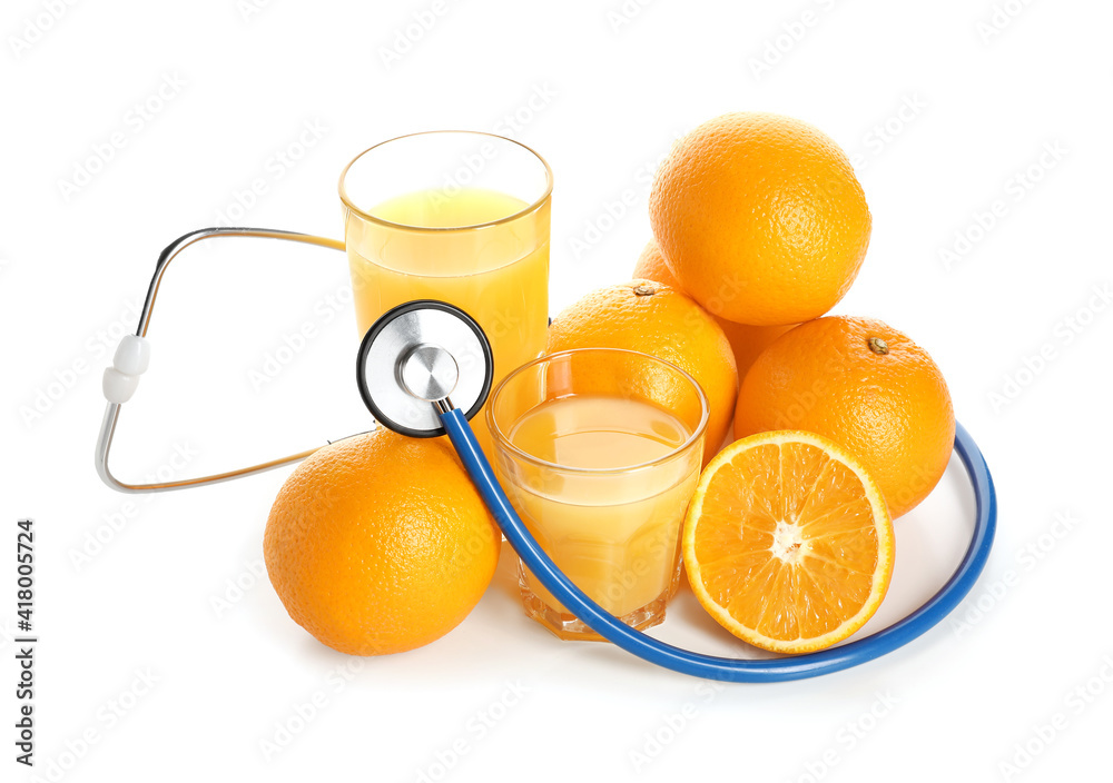 Fresh oranges, glasses of juice and  stethoscope on white background
