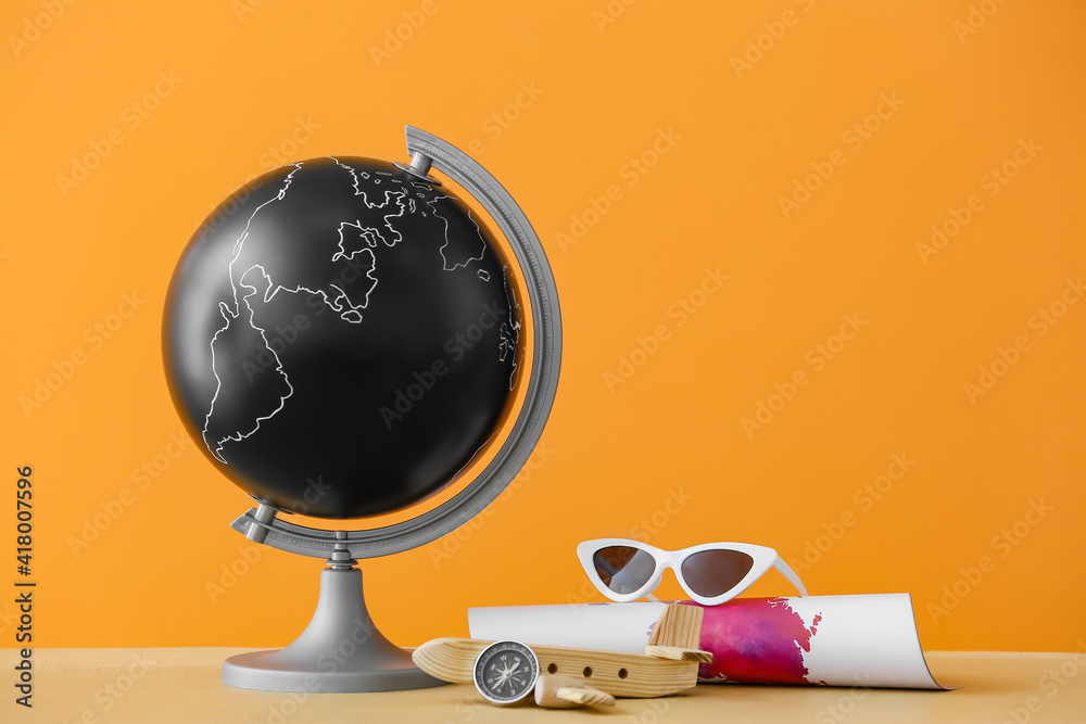 Globe, beach accessories and wooden airplane on color background