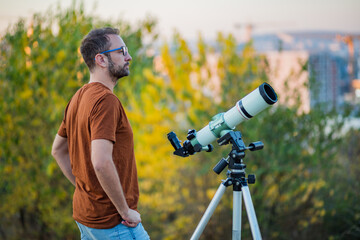 Wall Mural - amateur astronomer looking at the sky with a telescope.
