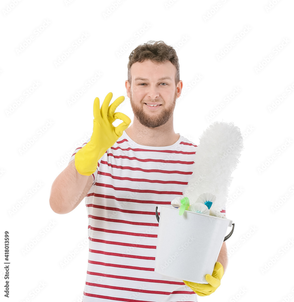 Young man with cleaning supplies showing OK on white background