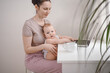 © Алина Троева - Young mother work studying from home with laptop computer during quarantine, little cute toddler baby on lap. Home office, parenthood. Remote work, distance education. Video conference virtual event.
