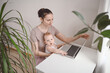 © Алина Троева - Young mother work studying from home with laptop computer during quarantine, little cute toddler baby on lap. Home office, parenthood. Remote work, distance education. Video conference virtual event.