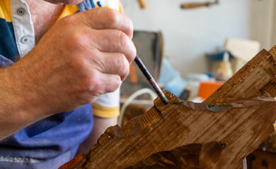 Elderly repairman painting with paintbrush on a small business a woodwork. Senior artisan with big hand painting artwork. Carpenter make handcraft. Male Aged builder working on manual renovation