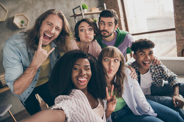 Wall Mural - Photo portrait of smiling friends showing v-sign heavy metal gestures taking selfie grimacing silly faces