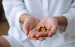 © Farknot Architect - Closeup image of a woman holding red and yellow colors medicine capsules in hands