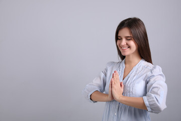 Canvas Print - Young woman meditating on grey background, space for text. Stress relief exercise