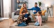 Caucasian lovely happy family gathered at home together. Mother and father sitting on sofa and drinking coffee watching their little kids girl and boy playing with cute animal puppy, home pet concept