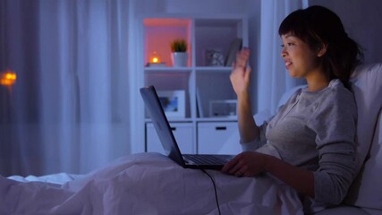 Sticker - technology, internet, communication and people concept - young asian woman with laptop computer having video call in bed at home at night