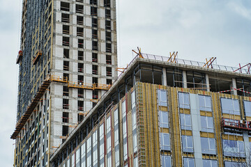 Wall Mural - Residential high-rise building under construction. Unfinished house on a construction site with cranes.