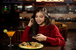 Portrait of a pretty young girl checking her phone while having lunch at the restaurant.