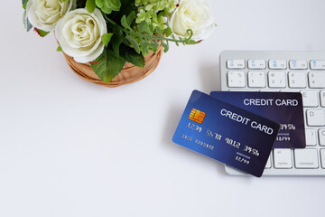 Credit card on computer keyboard and flowerpot on white desk. with copy space for text. Concept of Online shopping and payment.