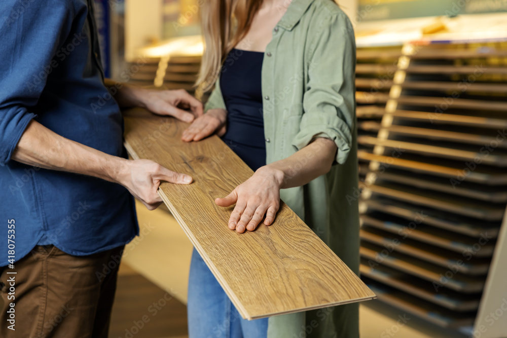 young couple choosing laminate floor design together for new house interior in flooring store - obrazy, fototapety, plakaty 