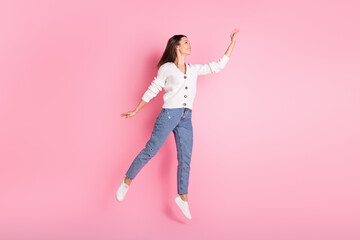 Wall Mural - Full length photo of happy charming young lady jump up reach empty space isolated on pink color background