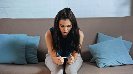 Wall Mural - shocked young woman holding pregnancy test at home