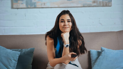 Wall Mural - young woman watching tv and smiling at home