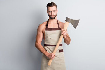 Poster - Portrait of attractive fit content athletic guy wearing apron holding in hand wooden ax isolated over light grey pastel color background