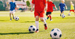 © matimix - Sporty children on football summer camp. Kids practicing football on grass field. Football soccer children training class. Group of school children running and kicking soccer balls on training camp