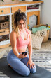 © simona - Shot of fitness woman sitting on yoga mat and using mobile phone. Fit young woman using cellphone while doing exercise at home. online class lesson sporty people with healthy lifestyle