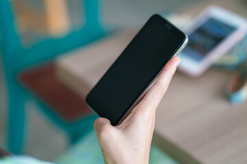 Woman hand holding smartphone black screen sittin in modern coffee shop