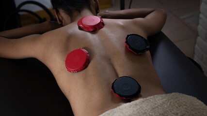 Brunette woman lying on a therapeutic stretcher with biomagnetism therapy magnets placed on her back to treat her health with holistic therapies and alternative medicine