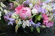 Bunte Frühlingsblumen im Gesteck schmücken ein Grab nach Beerdigung