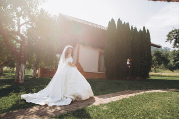 Wall Mural - Wedding at an old winery villa in Tuscany, Italy. The bride in a white magnificent dress, with bare shoulders and magnificent sleeves, walks on the garden.