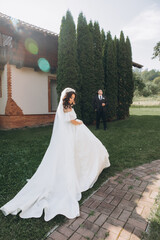 Wall Mural - Wedding at an old winery villa in Tuscany, Italy. The bride in a white magnificent dress, with bare shoulders and magnificent sleeves, walks on the garden.