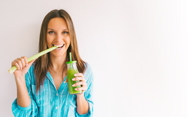 Healthy detox vegan diet. Young beautiful woman with stick of green organic celery and fresh homemade celery juice. Healthy eating and drinking lifestyle. White free space for text. Copy space