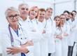 © ASDF - senior female doctor standing in front of her colleagues.