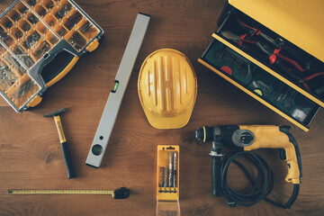 Wall Mural - Construction worker equipment. High angle view of helmet, drill machine, level, meter and other tools