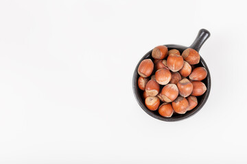 Wall Mural - Fresh shelled hazelnuts in a black bowl isolated on white background.