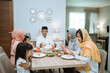 © Odua Images - muslim people praying during iftar dinner together with family in the kitchen at home