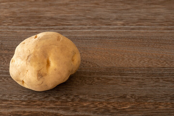 A potato on a dark brown wooden table